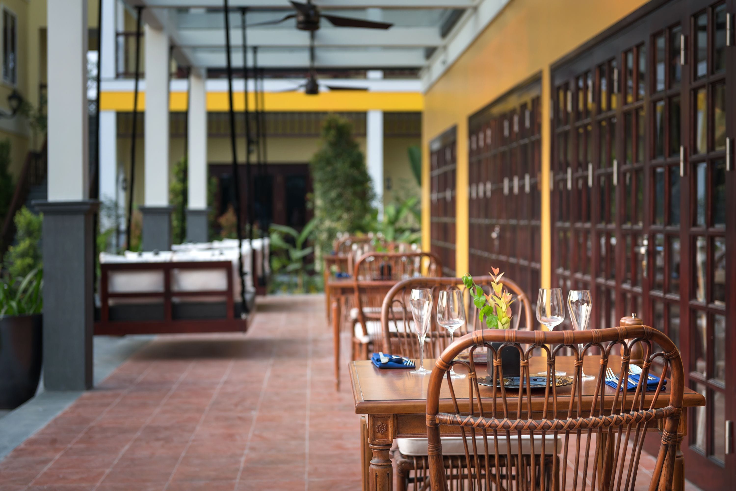 A restaurant with outdoor seating, wooden tables, and chairs.