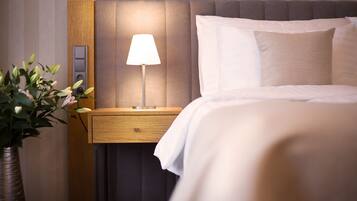Ein Hotelzimmer mit einem Bett, einem Nachttisch mit Lampe und einer Vase mit Blumen.
