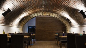 A restaurant with brick arches and wooden walls, featuring tables and chairs arranged for dining. - Hotel Schwaiger (Prague)