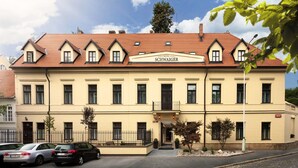 A hotel with a classic architectural style, featuring a symmetrical facade, multiple windows, and a red-tiled roof. - Hotel Schwaiger (Prague)