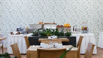 Un buffet per la colazione con diversi cibi, una macchina per il caffè e un'esposizione di frutta.
