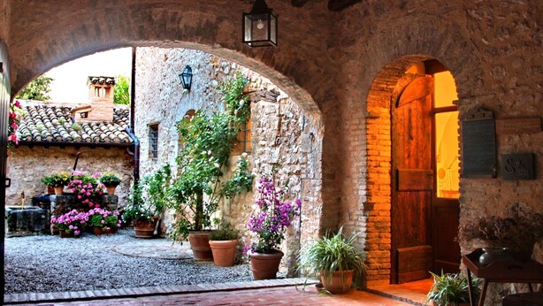 An arched stone courtyard with potted plants and a rustic wooden door. - Scenic Stay in Spoleto (Spoleto)