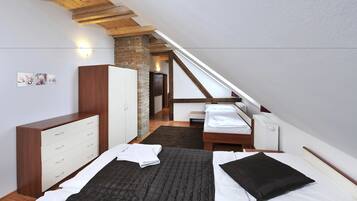 Et soveværelse med loftstil, der indeholder en seng, et garderobeskab og et lille skrivebord.