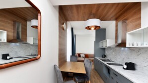 Una cocina moderna con techo de madera, encimera de mármol y zona de comedor con sillas tapizadas en gris.