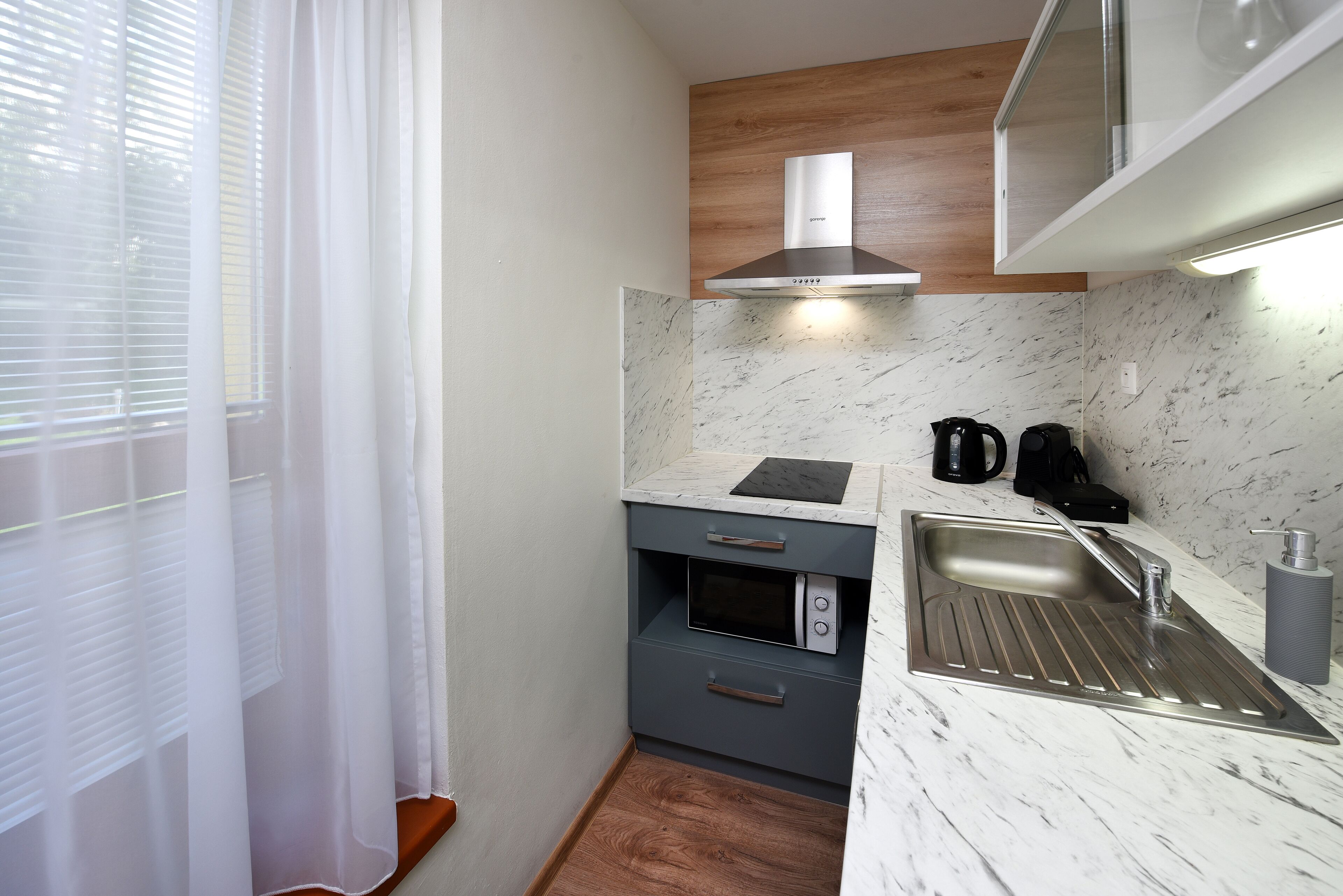 Une cuisine compacte dotée d’un four encastré, d’un évier en acier inoxydable et d’un plan de travail en bois.