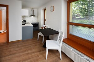 Una cocina compacta con comedor, un reloj en la pared y una ventana con persianas.