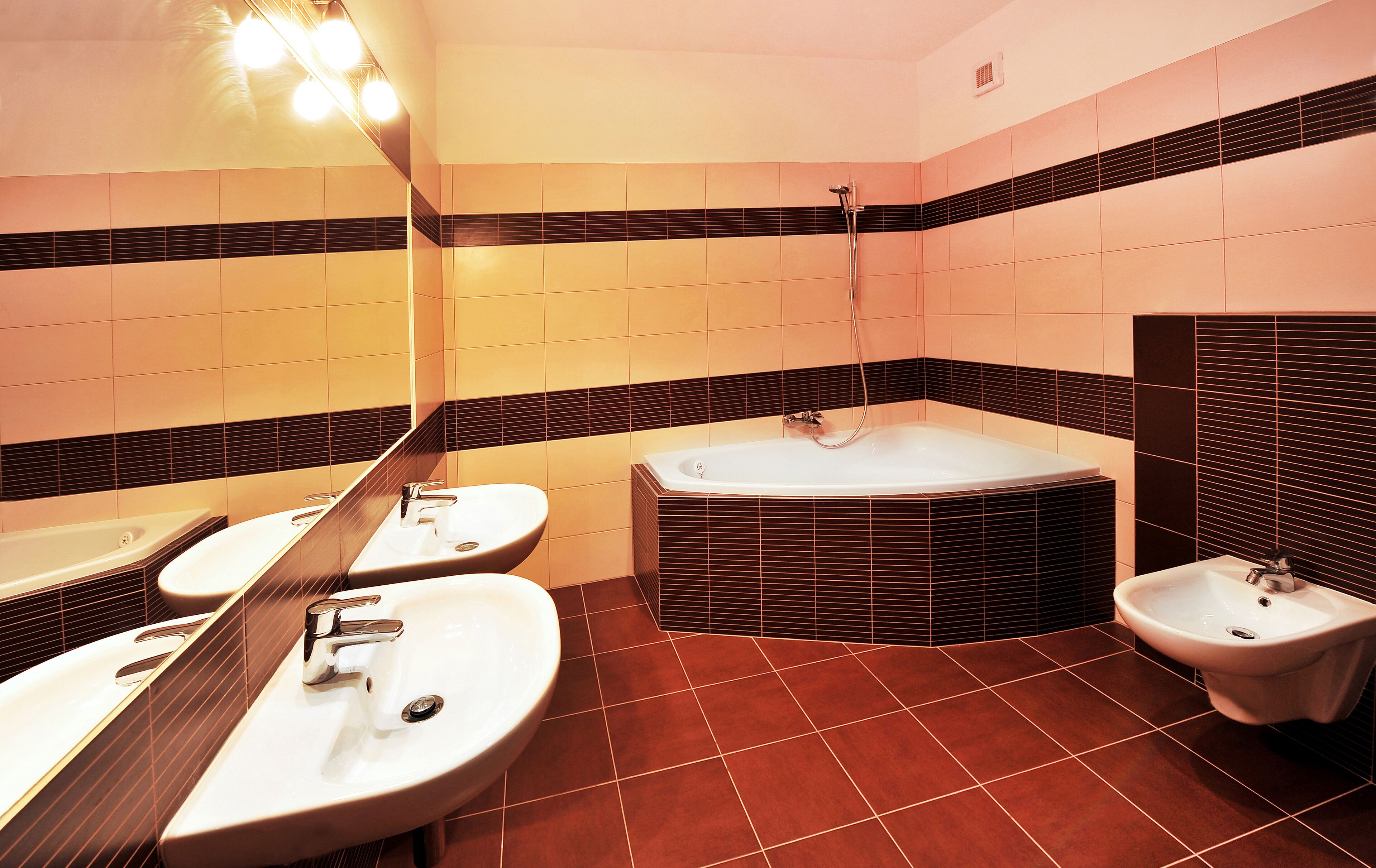 Ein Badezimmer mit drei Waschbecken, einer Badewanne und einem Bidet.