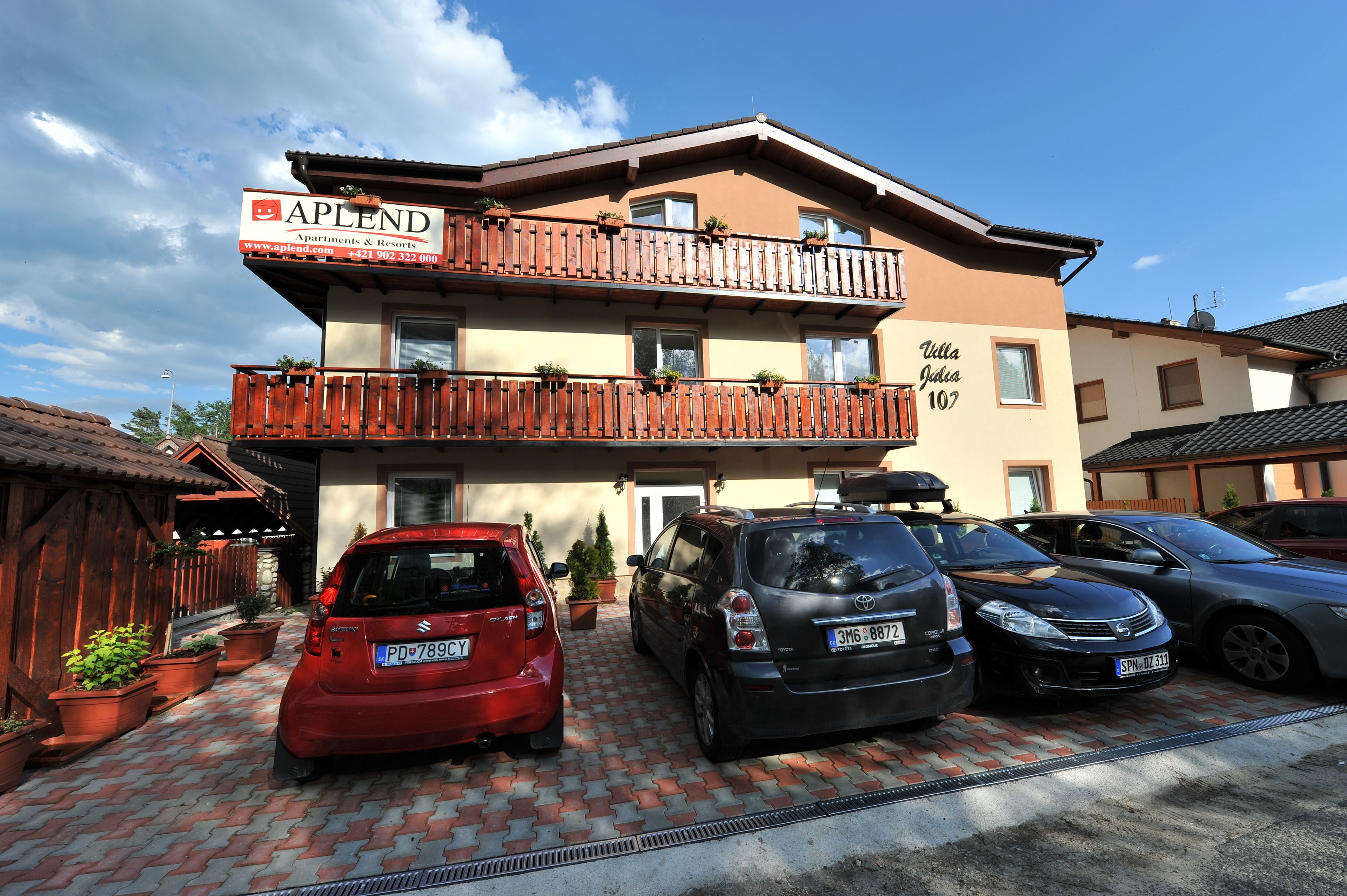 A building with a sign for APLEND Apartments & Resorts, featuring a two-story structure with a wooden balcony and potted plants.