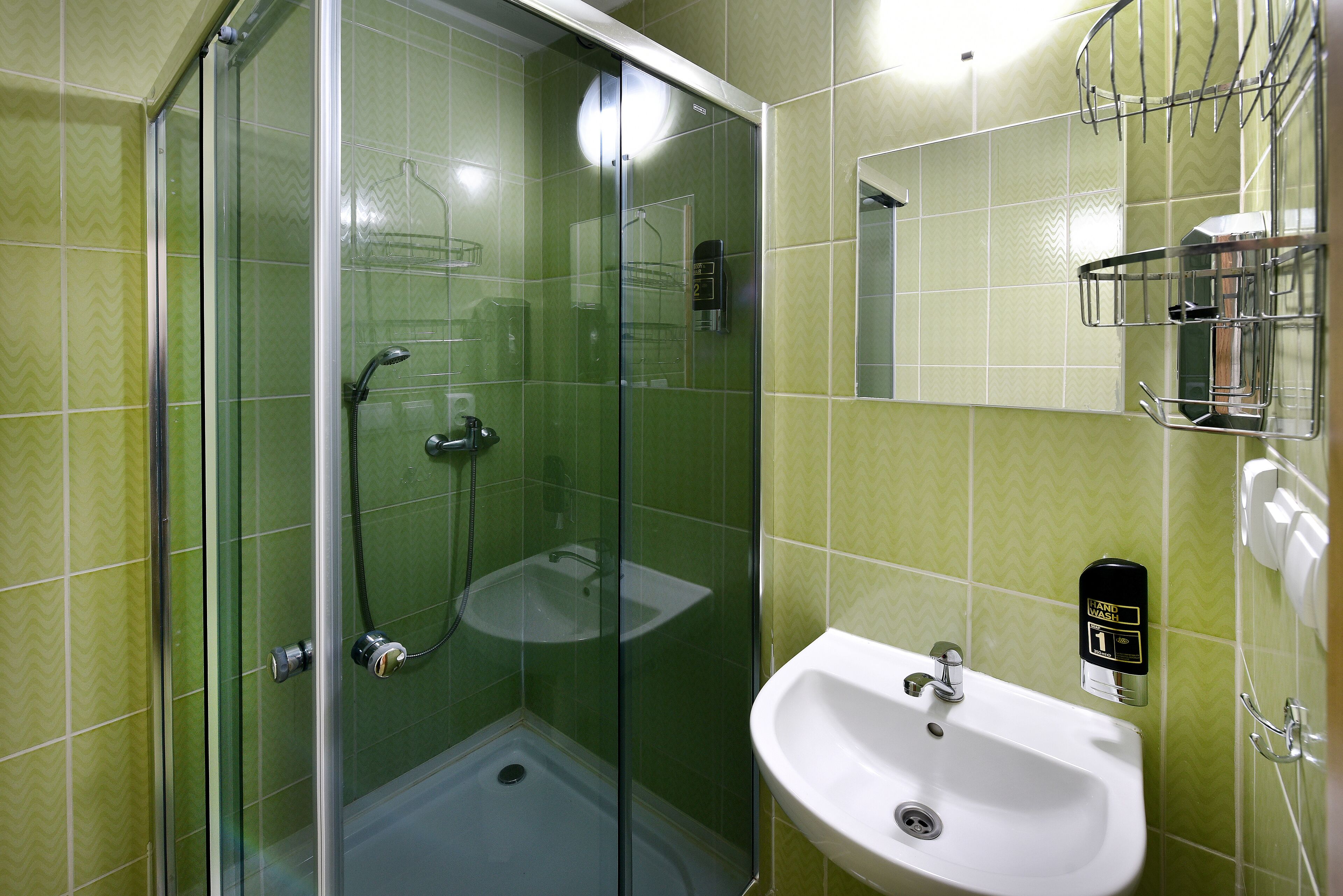 Un baño con ducha acristalada, lavabo y espejo.