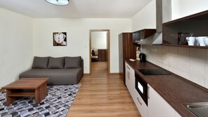 A modern kitchen with a microwave, stove, and cabinets. There is a sofa and a coffee table in the living area. - APLEND Bed & Breakfast Júlia (Vysoké Tatry)