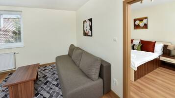 A compact room with a sofa, a small wooden table, and a bed with a wooden headboard.