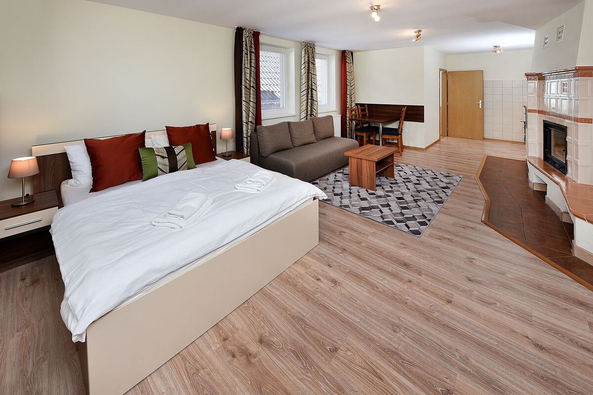 Habitación de hotel con cama, sofá, escritorio, chimenea y vistas al exterior.