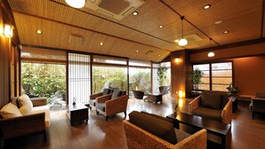 A spacious room with wicker furniture, large windows, and a wooden ceiling. - Hotel Ichiboukan (Kyotango)