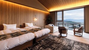 Habitación de hotel moderna con una cama grande, un sofá y un balcón con vistas a la ciudad.