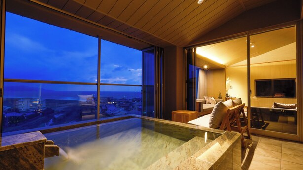 Un interior moderno con piscina infinita de vidrio, una zona de estar acogedora y un ventanal con vistas a la ciudad.