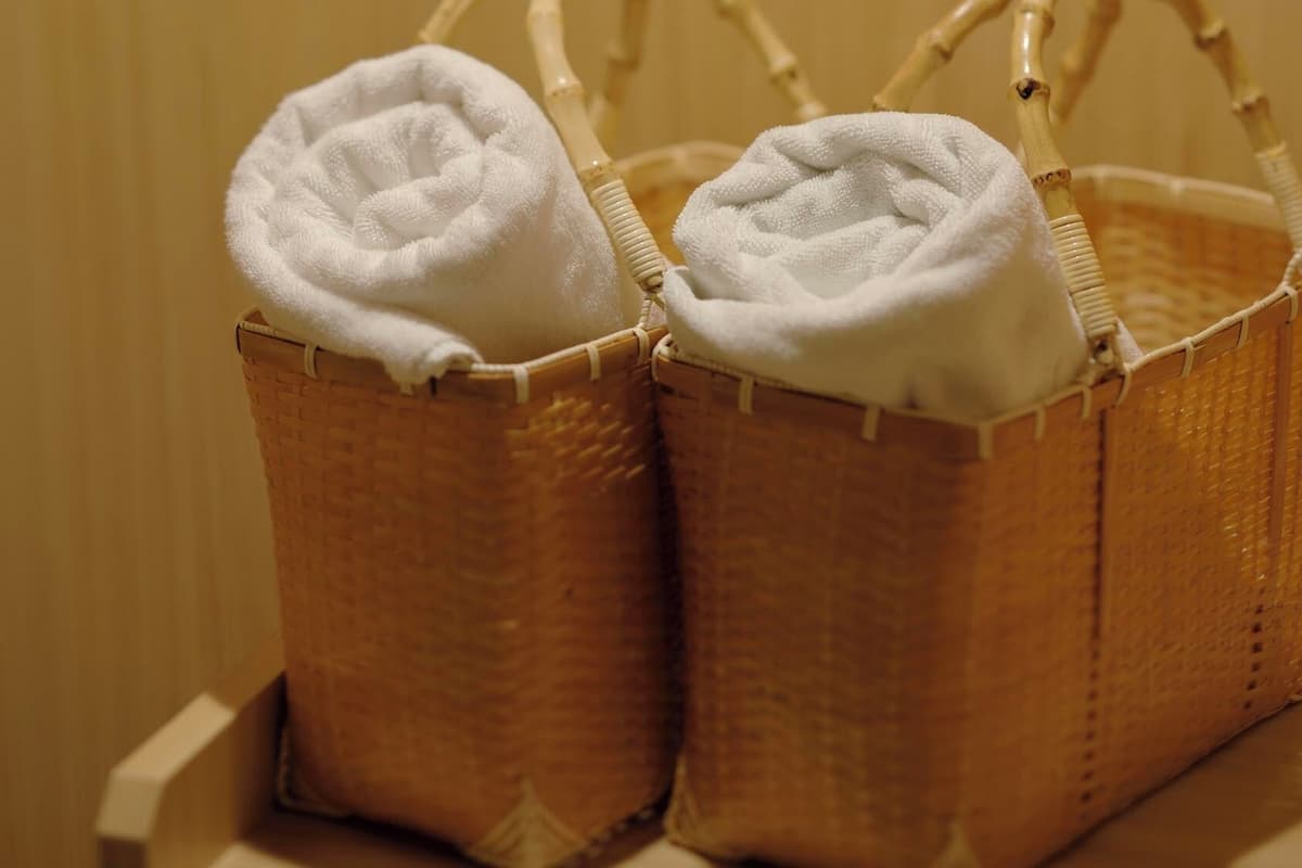 Two wicker baskets with white towels placed on a wooden surface.