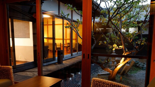 Quarto com porta de vidro deslizante que dá para área externa com deck de madeira e uma árvore.