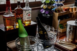 A bar area with various bottles of liquor, including bourbon and whiskey, and a selection of glasses and ice.