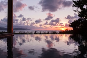 A sunset over a calm body of water with a wooden fence and distant mountains. - Yuhigaura Onsen Ryotei KAI (Kyotango)