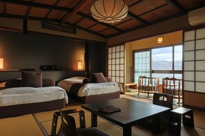 A traditional Japanese-style room with tatami flooring, two beds, a table, and a view of the mountains through large shoji doors. - Yuhigaura Onsen Ryotei KAI (Kyotango)