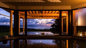 Quarto espaçoso com grandes janelas que oferecem vista para o mar e montanhas.