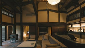 A spacious room with a fireplace, seating area, and a bar with shelves. -  Ujo Soan (Kyotango)