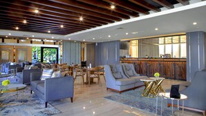 Un amplio vestíbulo de hotel con mobiliario moderno, una zona de bar y vistas al exterior.
