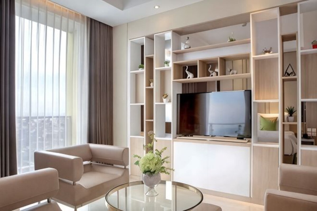 Una sala de estar moderna con televisor de pantalla plana, estanterías empotradas y una mesa de centro de vidrio.
