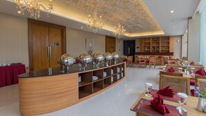 Un comedor amplio con un bufé central, paneles de madera y candelabros.