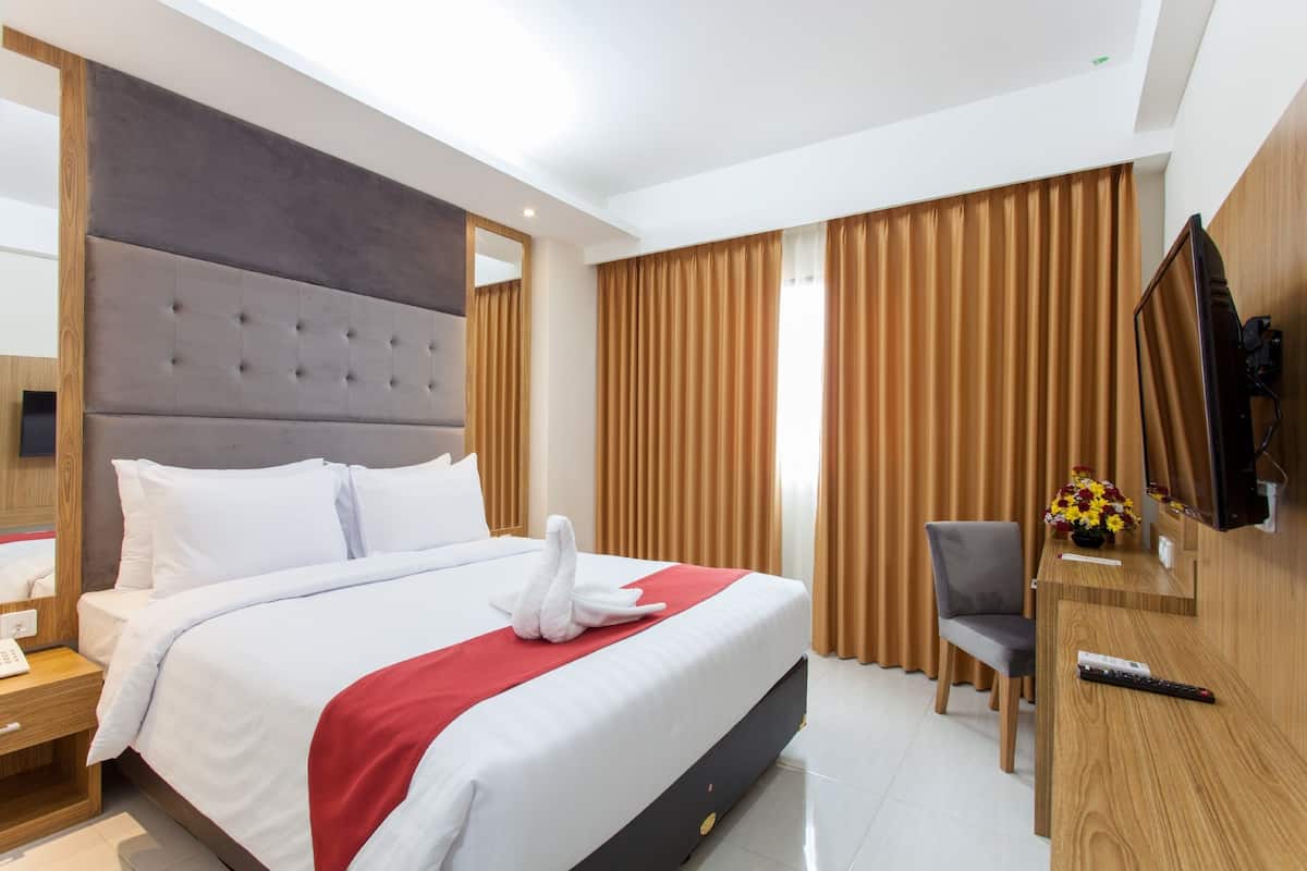 Une chambre d’hôtel avec un grand lit, un bureau en bois, une télévision et une chaise.
