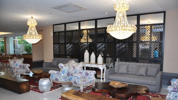 Un vestíbulo espacioso con un sofá gris, sillones con estampado floral y una mesa de centro de madera.