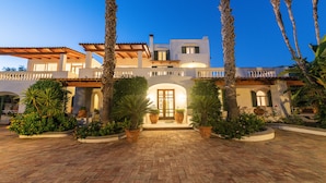 A two-story building with a tiled roof, a central entrance with a door, and a paved courtyard with potted plants. - Residence San Domenico (Forio)