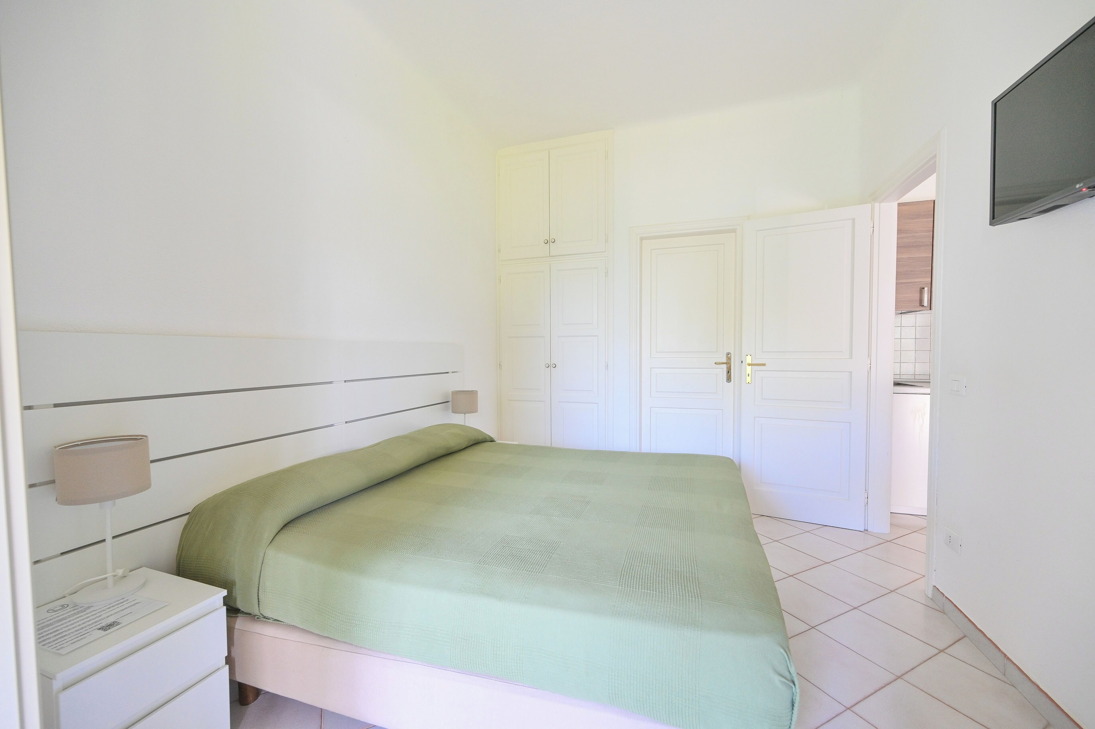 Un dormitorio con una cama, una mesita de noche, una lámpara y un armario.