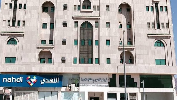 A large, multi-story building with a central arched window and multiple smaller windows.
