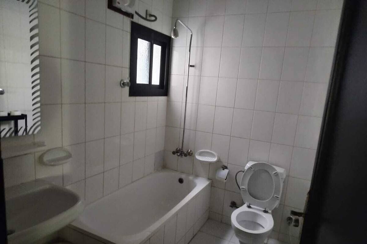 A standard bathroom with a bathtub, toilet, sink, and a window.