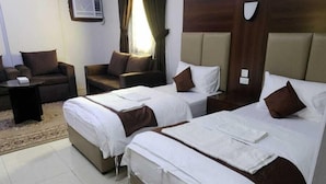 A hotel room with two beds, a sofa, a chair, and a small table.