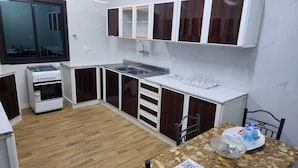 A compact kitchen with a built-in oven, a sink, and a dining area with a table and chairs.