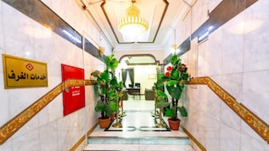 A marble staircase with red signage and potted plants, leading to a reception area.