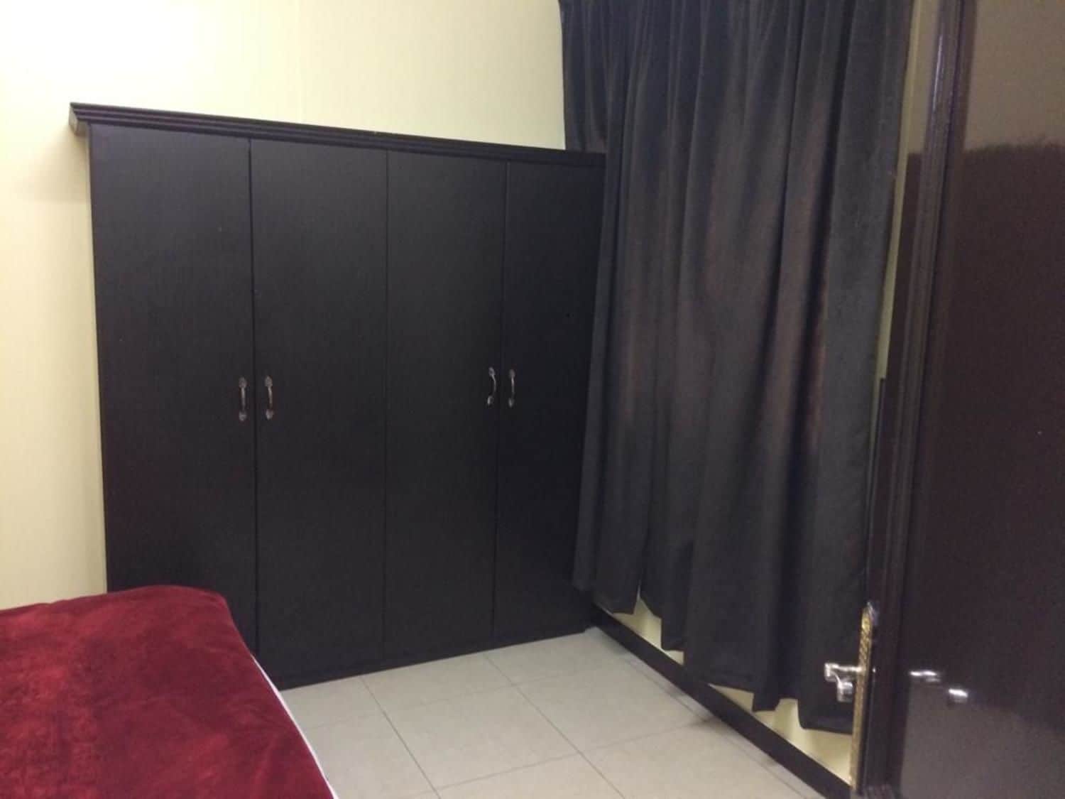 A room with a bed, a wardrobe, and a door.