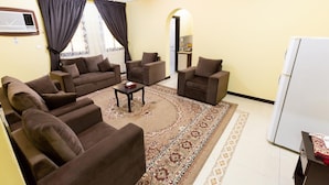 A living room with a sofa set, armchairs, a coffee table, and a patterned rug.