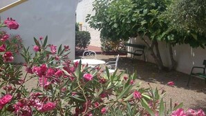 Um pátio com uma parede branca, um banco e uma mesa.