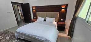 Une chambre d’hôtel dotée d’un grand lit, d’une tête de lit en bois avec éclairage intégré, d’une table de chevet et d’une petite table à côté du lit.