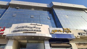 A modern building with a glass facade and multiple signs, including one for 'Ala'ry Serviced Apartments. - Al Eairy Serviced Apartments Company  (Buraydah)