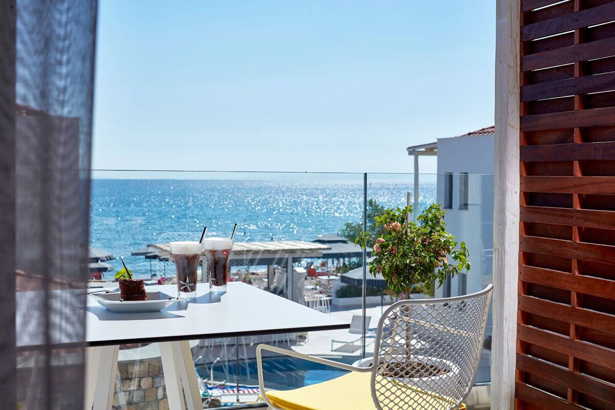 A balcony with a table, chairs, and a view of the sea.