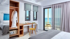 Et moderne hotelværelse med seng, skrivebord, stol, garderobeskab og en balkon med havudsigt.