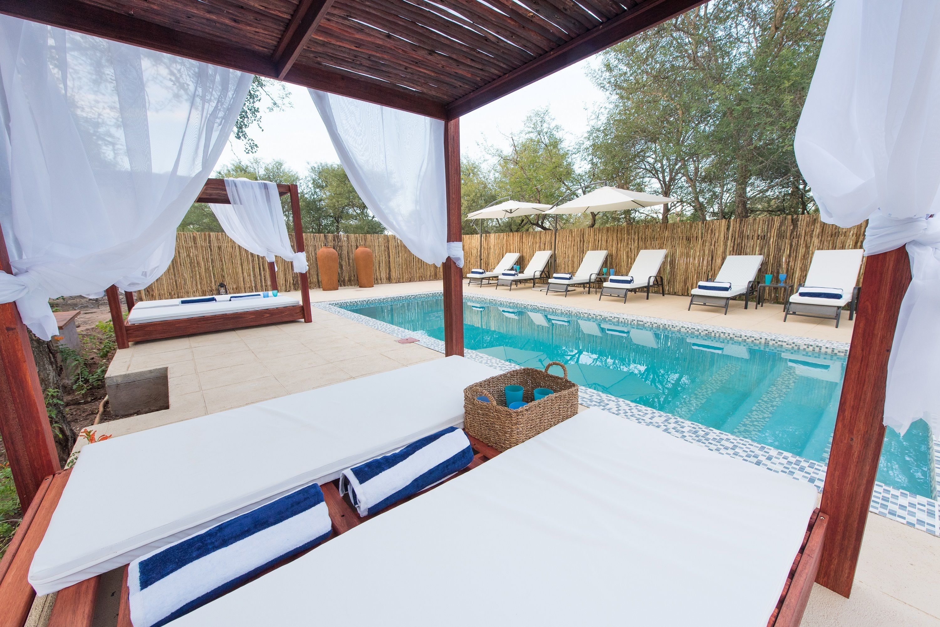 Una piscina al aire libre, sombrillas, sillones reclinables de piscina