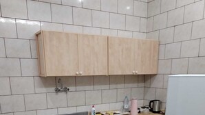 Une petite cuisine équipée d’un évier, de placards, d’un réfrigérateur et d’une table avec des chaises.