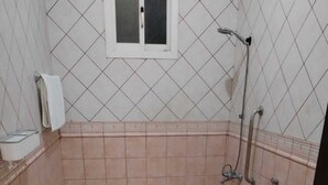 Une salle de bain équipée de toilettes, d’une barre d’appui, d’une fenêtre et d’une douche.