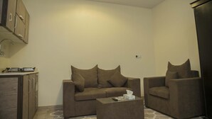 A compact living space with a sofa set, a coffee table, and a kitchenette area.