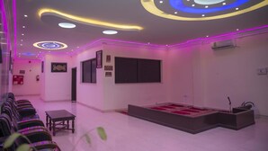 A hotel lobby with a reception desk, seating area, and a stage for presentations.